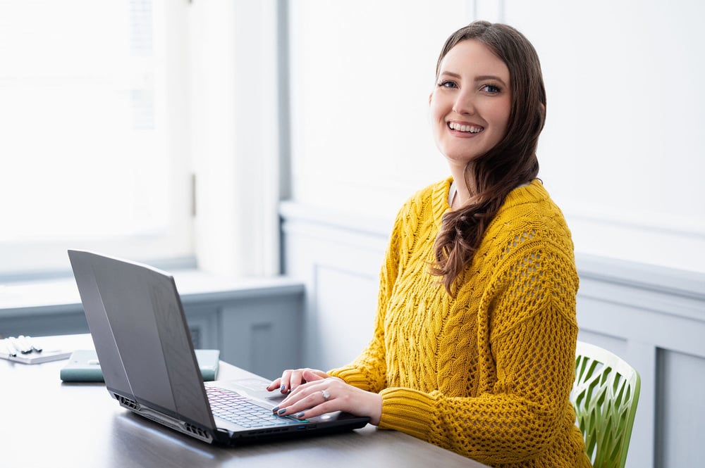 KF sitting at her laptop and smiling at the camera